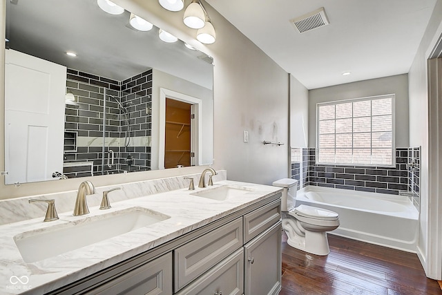 2308 Nowland Ave, Indianapolis, IN 46201 - bathroom featuring visible vents, tiled shower, a sink, and wood finished floors