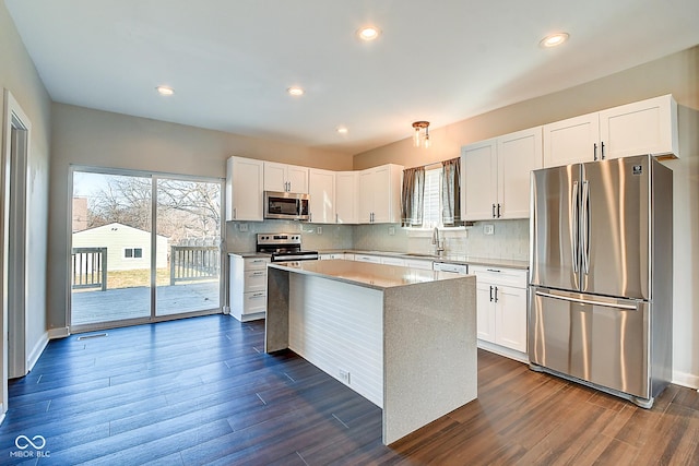 2308 Nowland Ave, Indianapolis, IN 46201 - kitchen featuring decorative backsplash, dark wood-style flooring, a center island, stainless steel appliances, and white cabinetry