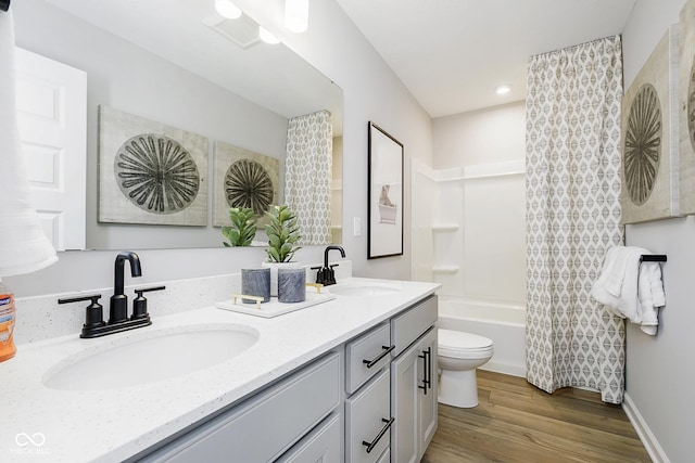 bathroom featuring double vanity, a sink, toilet, and wood finished floors