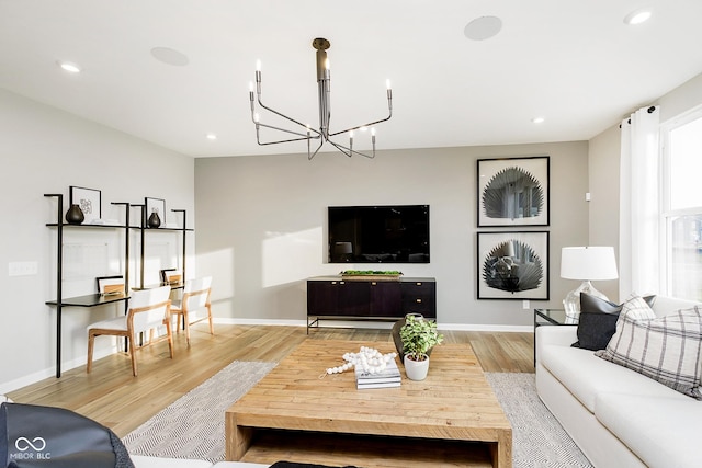 living room featuring an inviting chandelier, light wood-style flooring, and baseboards