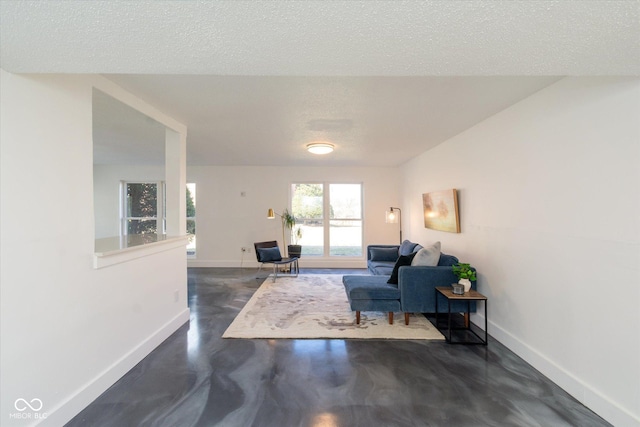 living area featuring a textured ceiling, concrete floors, and baseboards