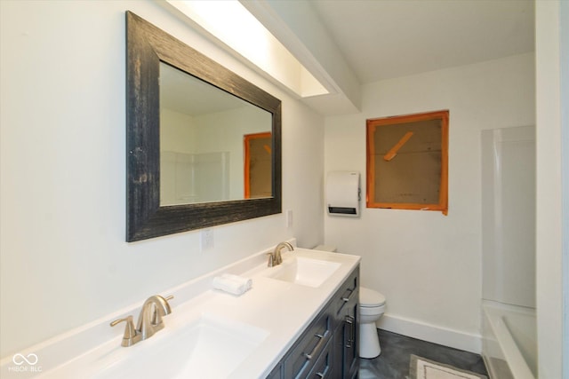 bathroom with double vanity, a sink, toilet, and baseboards