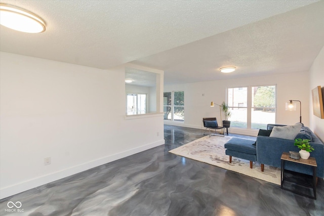 living area with plenty of natural light, a textured ceiling, baseboards, and concrete flooring