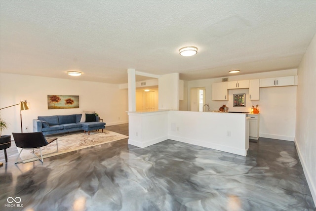 living room featuring a textured ceiling, baseboards, and concrete flooring