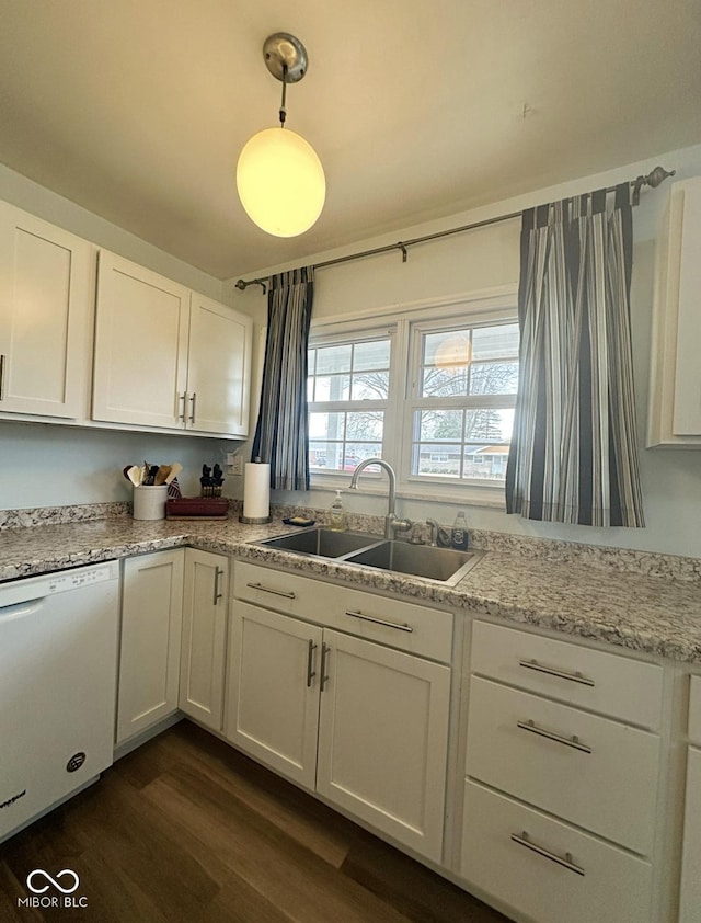 kitchen with white dishwasher, white cabinetry, and a sink