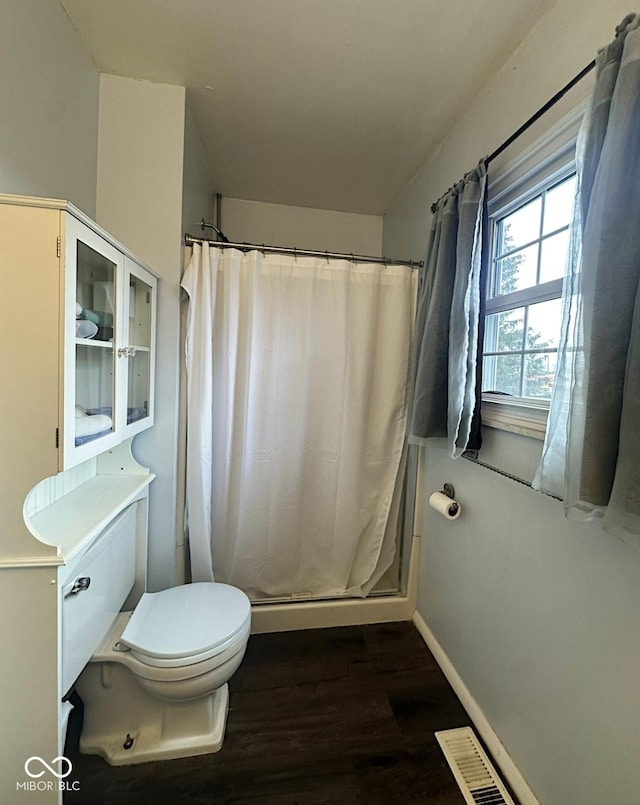 bathroom featuring toilet, a shower with shower curtain, wood finished floors, and visible vents