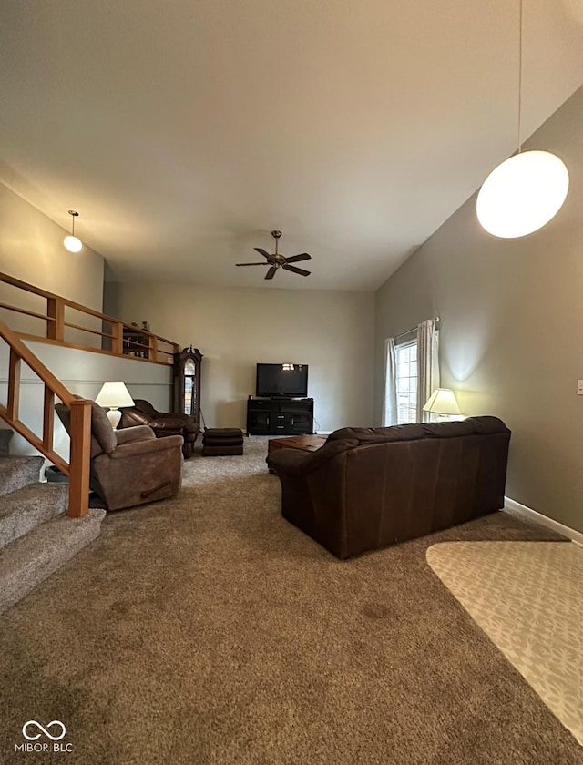 living room with stairway, carpet flooring, a ceiling fan, and baseboards