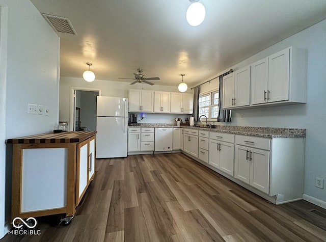 kitchen featuring white appliances, dark wood-type flooring, a sink, visible vents, and white cabinetry