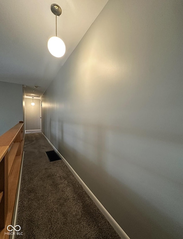 hall with dark colored carpet, visible vents, and baseboards