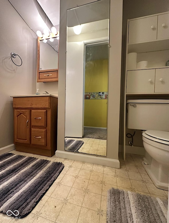 bathroom with baseboards, vanity, and toilet