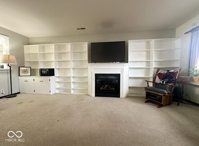 carpeted living area featuring a glass covered fireplace and visible vents