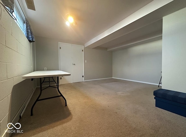 basement featuring concrete block wall, baseboards, and light colored carpet