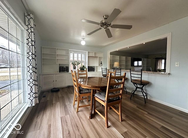 dining area featuring wood finished floors, a ceiling fan, and baseboards