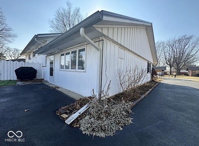 view of side of home featuring driveway and fence