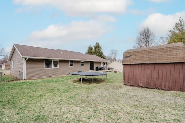 back of property featuring a trampoline, an outbuilding, a yard, fence, and a shed