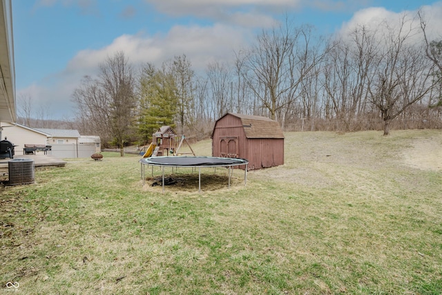 view of yard featuring a trampoline, a playground, central air condition unit, a storage unit, and an outdoor structure