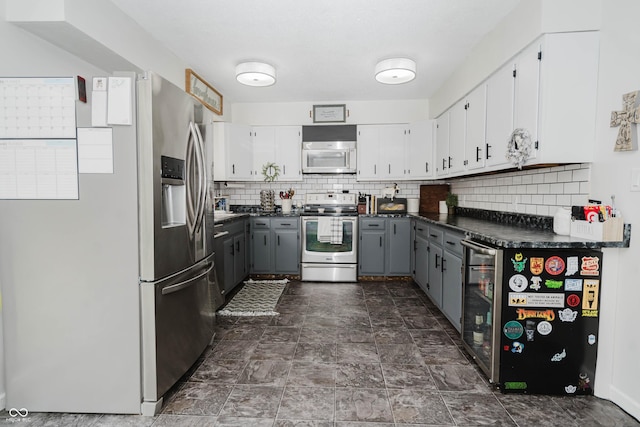 kitchen with stainless steel appliances, dark countertops, gray cabinets, and beverage cooler