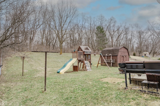 view of play area with a storage unit, a lawn, and an outbuilding