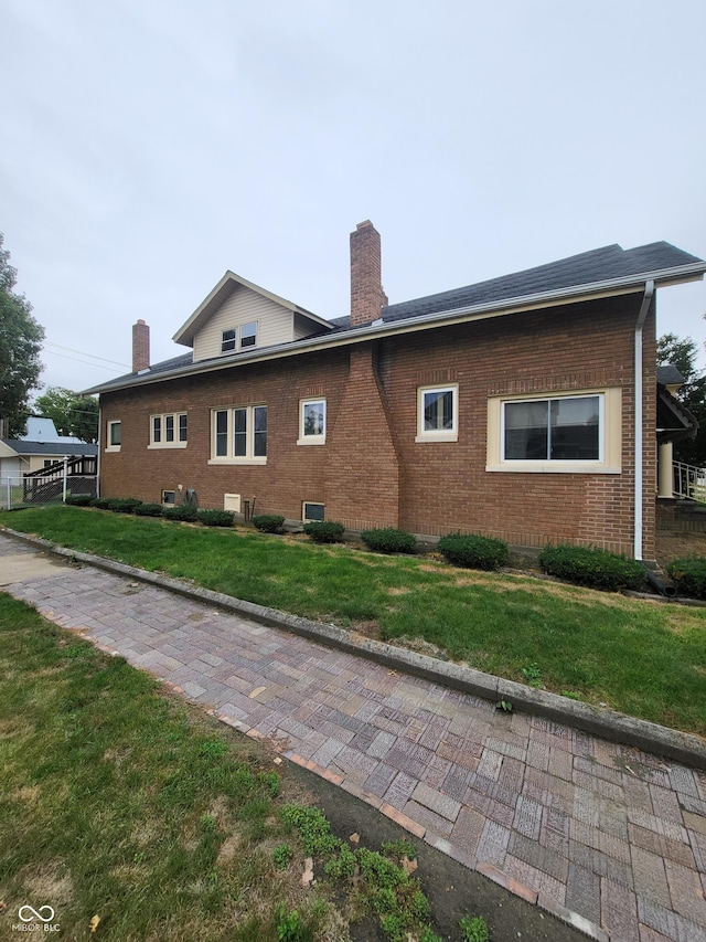 view of property exterior with a yard, brick siding, and a chimney