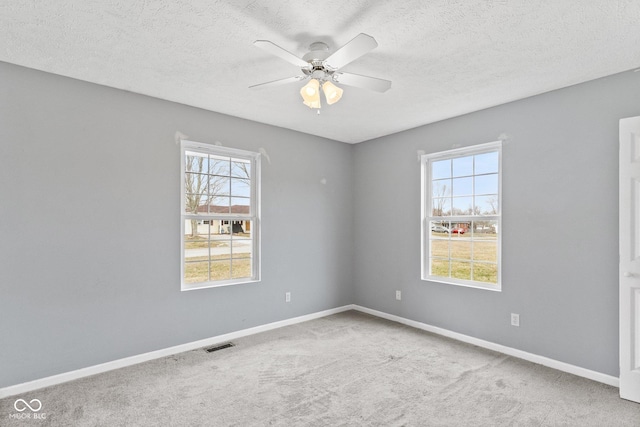 carpeted empty room featuring a healthy amount of sunlight, baseboards, and a ceiling fan