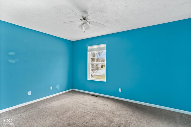 carpeted spare room with a ceiling fan, visible vents, a textured ceiling, and baseboards