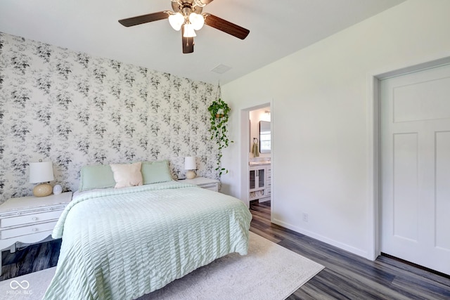 bedroom with wallpapered walls, an accent wall, baseboards, and wood finished floors