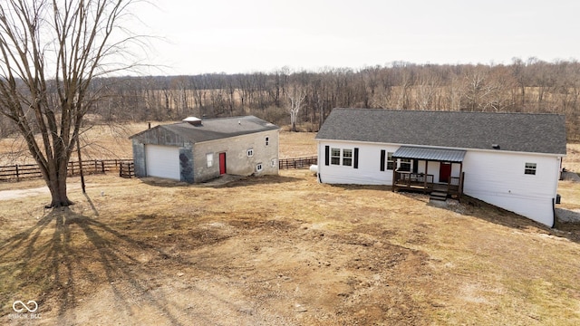 ranch-style home with a wooded view, a detached garage, fence, and an outdoor structure