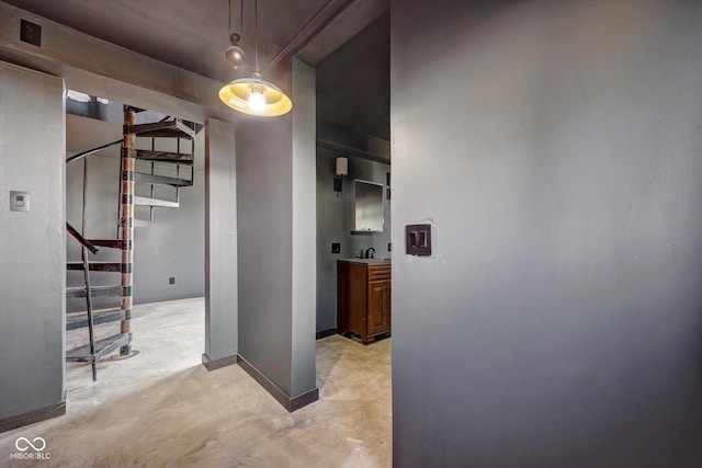 hallway featuring stairs, unfinished concrete floors, and baseboards