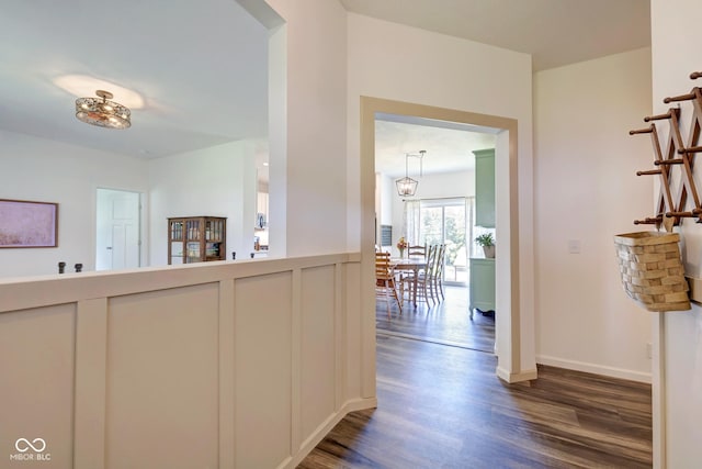 hallway featuring dark wood-style flooring and baseboards