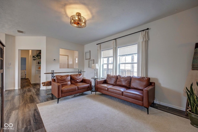 living area with visible vents, baseboards, dark wood finished floors, and a textured ceiling