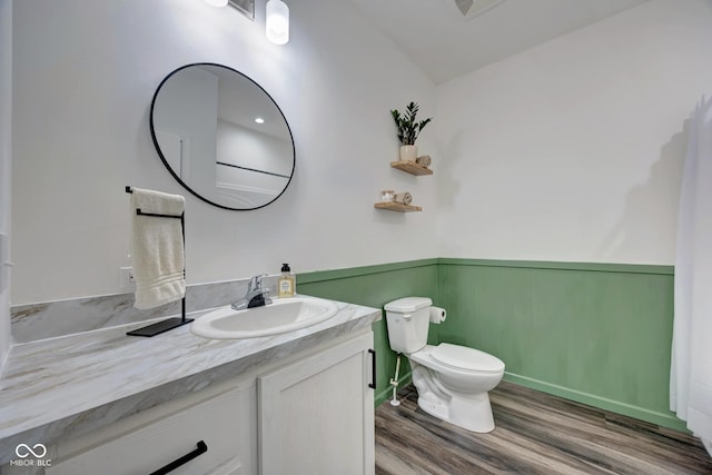 bathroom featuring wainscoting, vanity, toilet, and wood finished floors