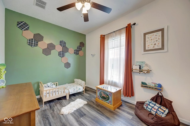 bedroom with ceiling fan, wood finished floors, visible vents, and baseboards