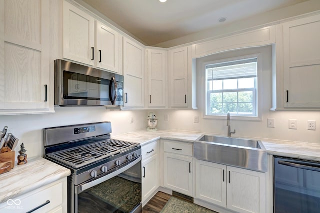 kitchen featuring appliances with stainless steel finishes, white cabinetry, a sink, and dark wood-type flooring