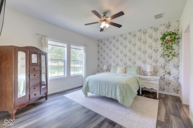 bedroom featuring baseboards, wood finished floors, visible vents, and wallpapered walls