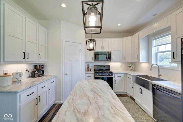 kitchen featuring stainless steel appliances, light stone counters, a sink, and white cabinetry