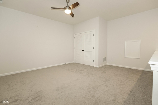 unfurnished room featuring carpet floors, visible vents, baseboards, and a ceiling fan