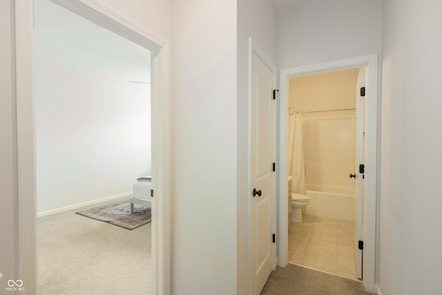 hall with baseboards, carpet flooring, and tile patterned floors