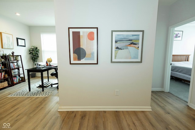 corridor featuring light wood-type flooring and baseboards