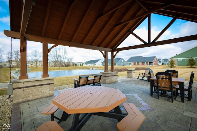 view of patio featuring a water view, outdoor dining space, and a gazebo