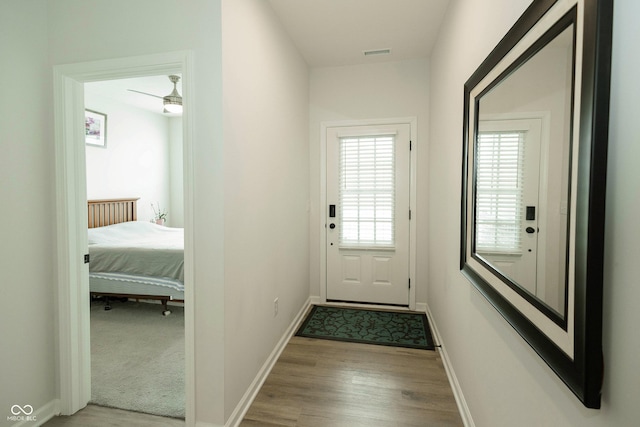 doorway to outside with wood finished floors, visible vents, and baseboards