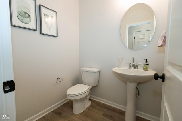 bathroom with wood finished floors, toilet, and baseboards