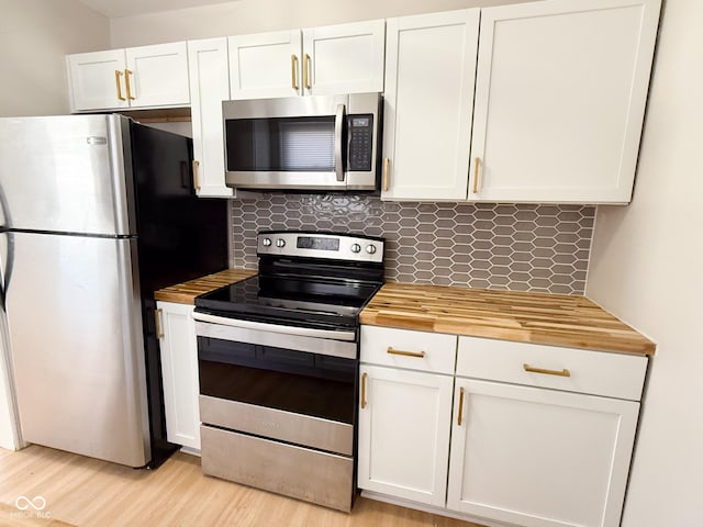 kitchen with stainless steel appliances, light wood-style flooring, decorative backsplash, white cabinets, and wood counters