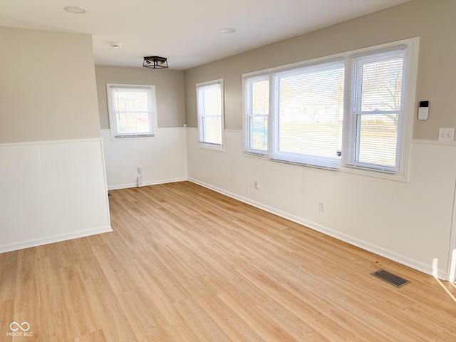 unfurnished room with wainscoting, visible vents, and light wood-style flooring