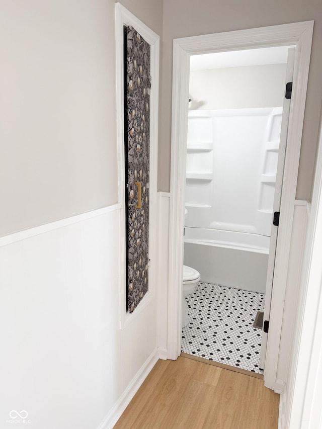 bathroom with wainscoting, wood finished floors, and toilet