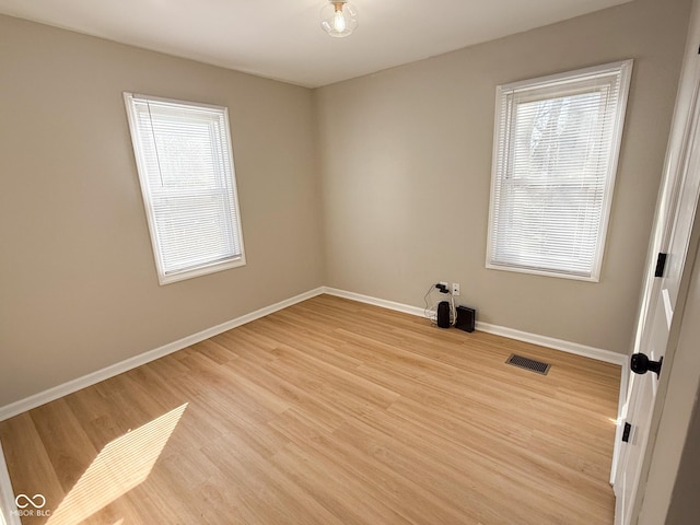 spare room featuring baseboards, visible vents, and light wood-style flooring