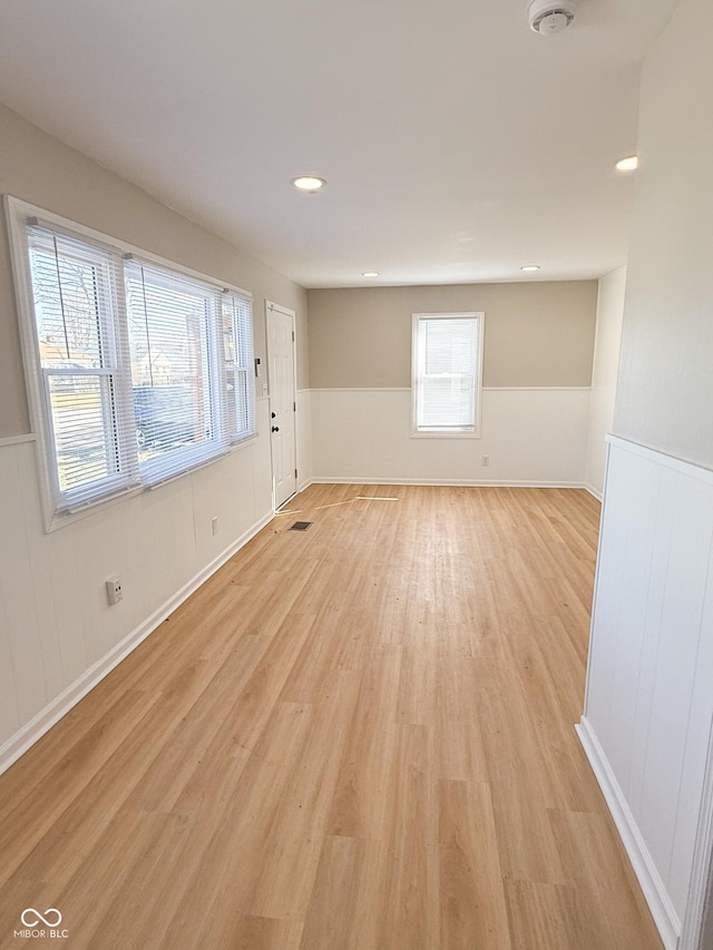 empty room featuring wainscoting, light wood-type flooring, and recessed lighting