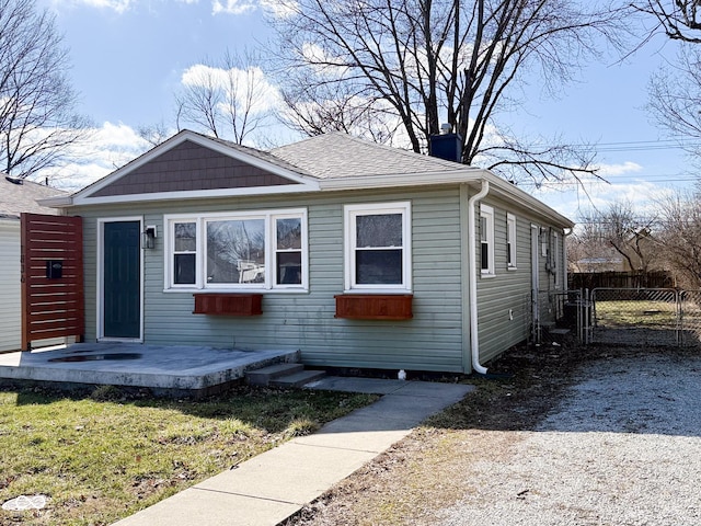 bungalow-style home featuring roof with shingles, fence, and a gate