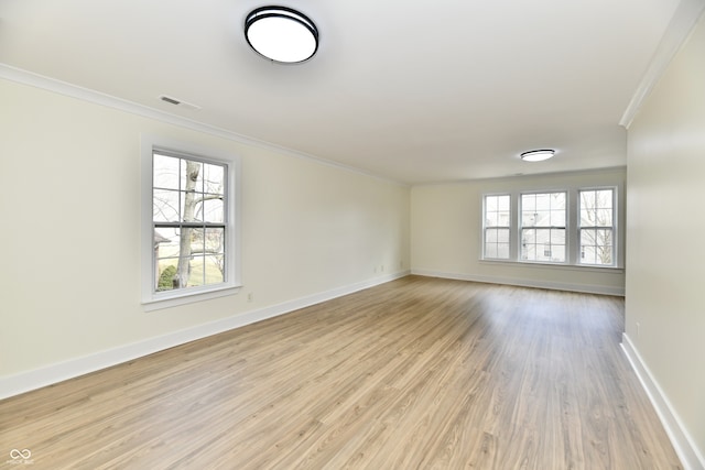 empty room with visible vents, baseboards, light wood-style floors, and ornamental molding