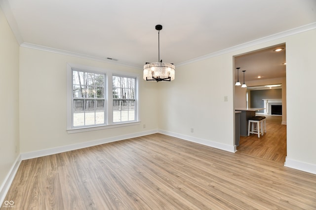 unfurnished dining area with light wood-type flooring, visible vents, a fireplace, crown molding, and baseboards