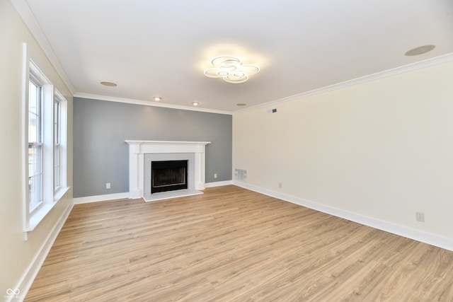 unfurnished living room featuring visible vents, a fireplace with raised hearth, crown molding, light wood finished floors, and baseboards